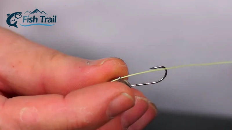 Threading fishing line through the eye of a mormyshka before tying a clinch knot